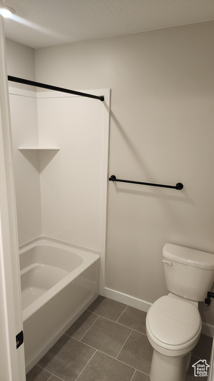 Bathroom with toilet, baseboards, tile patterned floors, and shower / bath combination