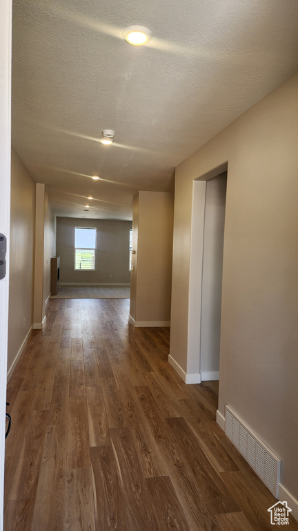 Hallway with dark wood-type flooring, baseboards, and a textured ceiling