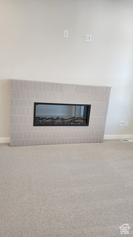 Detailed view of a fireplace, carpet floors, and baseboards