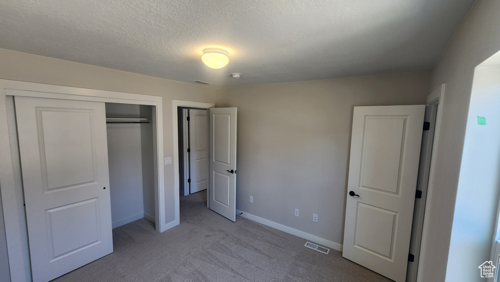 Unfurnished bedroom featuring carpet, a closet, baseboards, and a textured ceiling