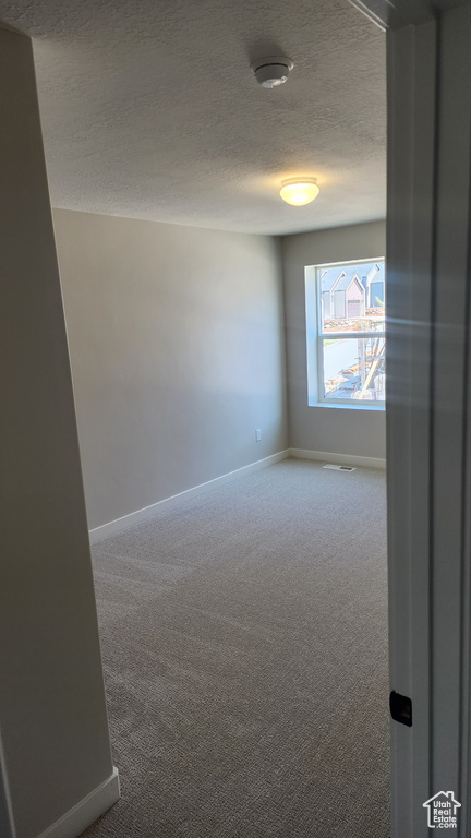 Unfurnished room featuring carpet floors, a textured ceiling, baseboards, and a smoke detector