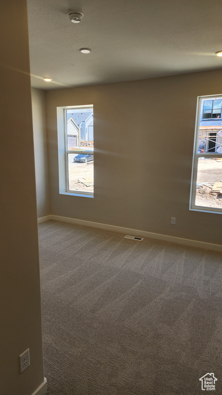 Carpeted empty room featuring baseboards and a smoke detector