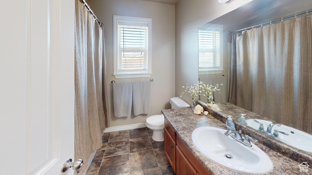 Bathroom with vanity, toilet, and baseboards