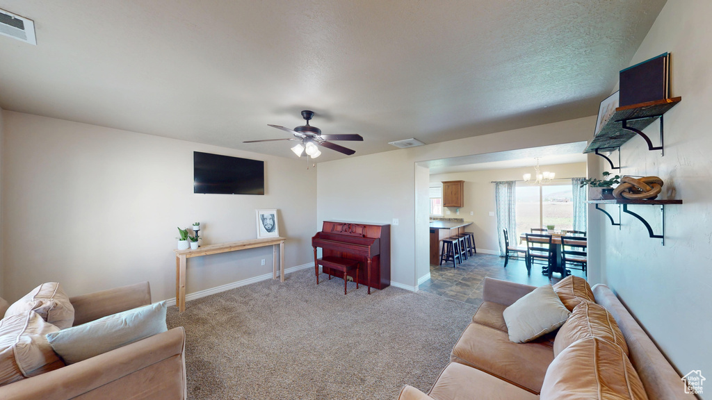 Carpeted living room with a chandelier, ceiling fan, and baseboards