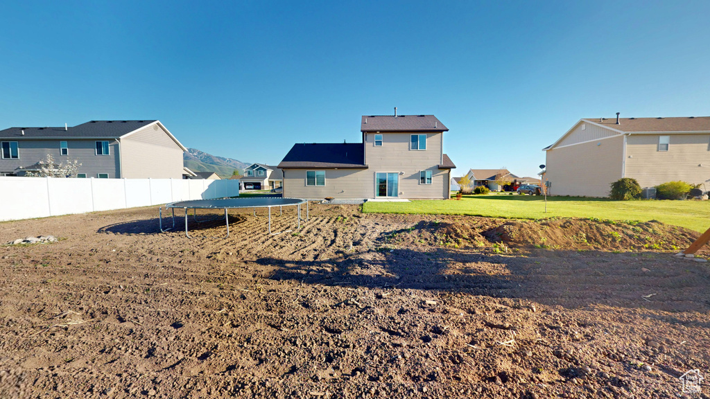 View of yard with a trampoline, fence, and a residential view