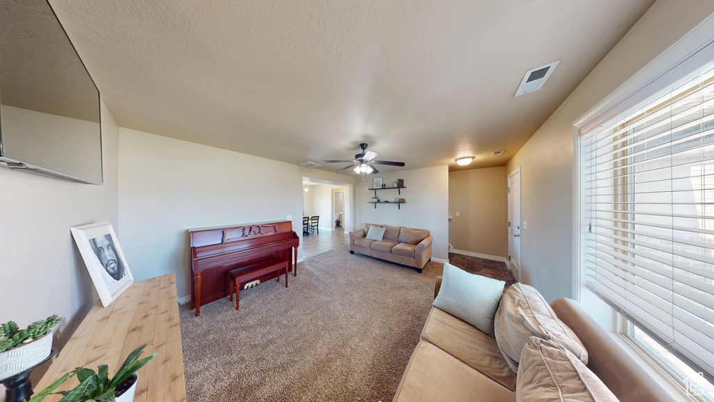 Carpeted living room featuring plenty of natural light, ceiling fan, and baseboards