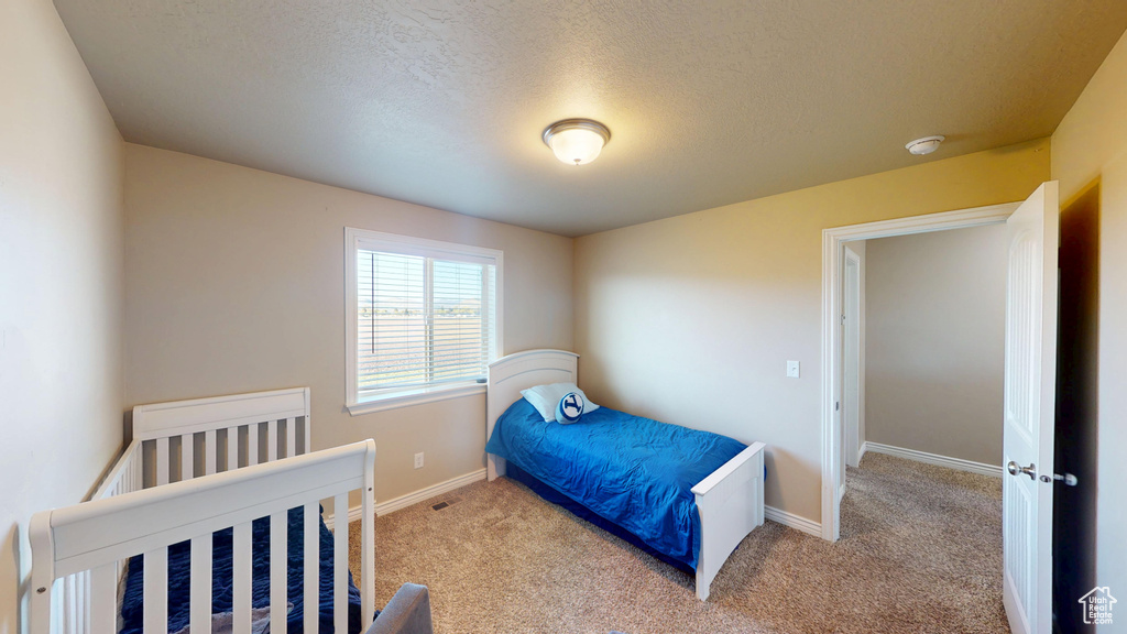 Bedroom featuring carpet, baseboards, and a textured ceiling