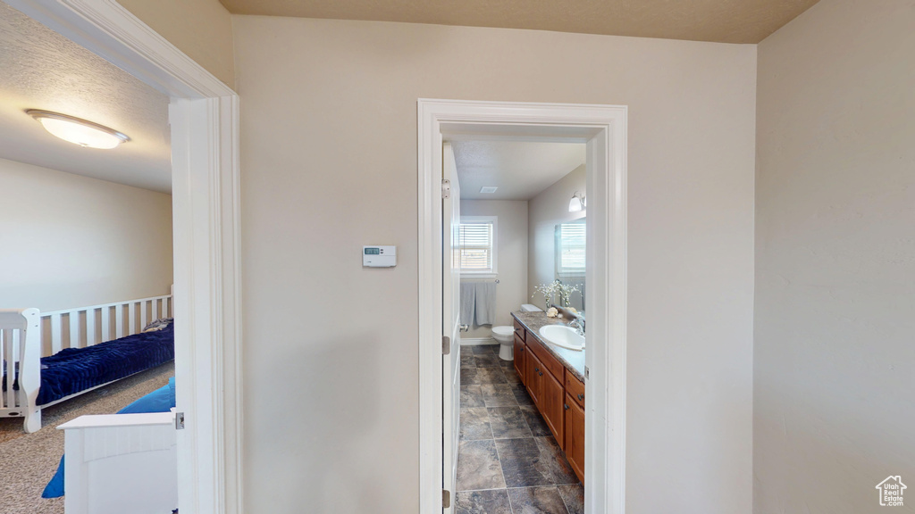 Bathroom with stone finish floors, vanity, baseboards, and toilet