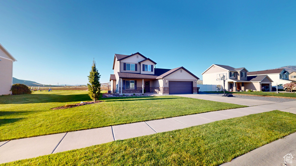 View of front facade featuring concrete driveway, a front yard, brick siding, and a garage
