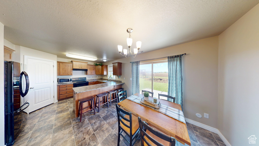 Dining room featuring a chandelier, stone finish flooring, baseboards, and a textured ceiling