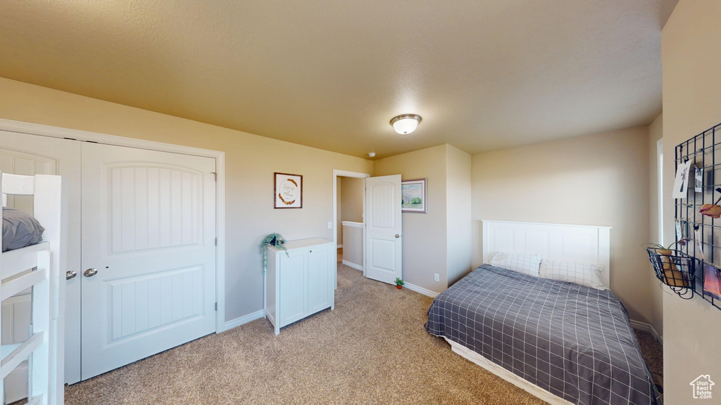 Bedroom with light carpet, baseboards, and a closet