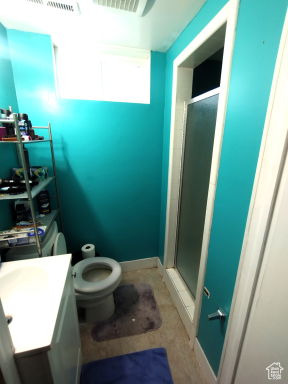 Bathroom with a stall shower, toilet, vanity, unfinished concrete floors, and baseboards
