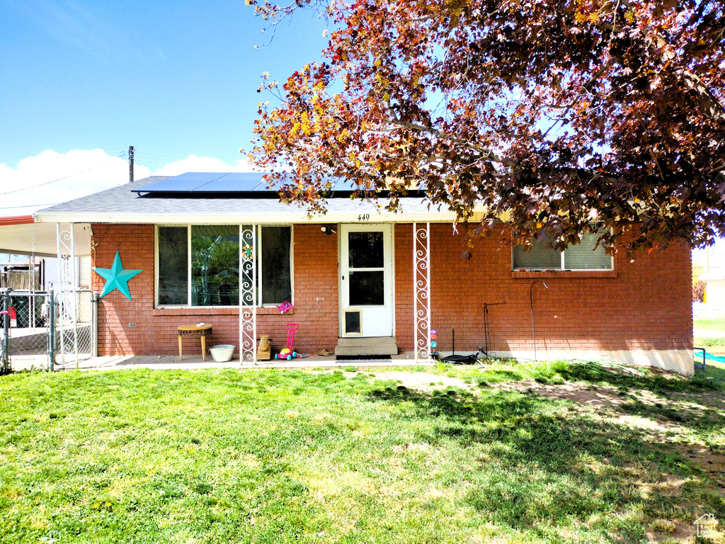 View of front of home with roof mounted solar panels, brick siding, a carport, and entry steps