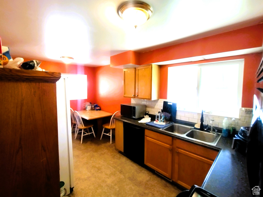 Kitchen featuring dishwasher, a sink, dark countertops, and backsplash