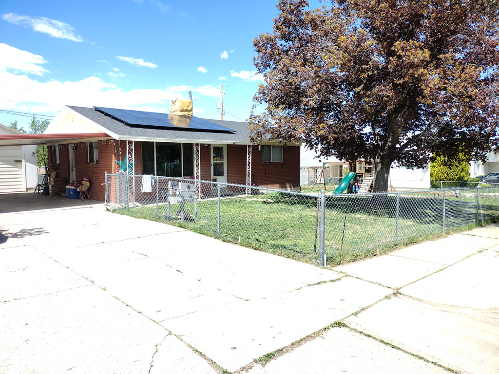 Single story home with driveway, a porch, an attached carport, brick siding, and roof mounted solar panels