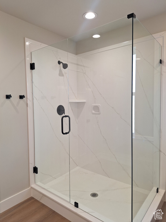 Full bath featuring a marble finish shower, wood finished floors, recessed lighting, and baseboards