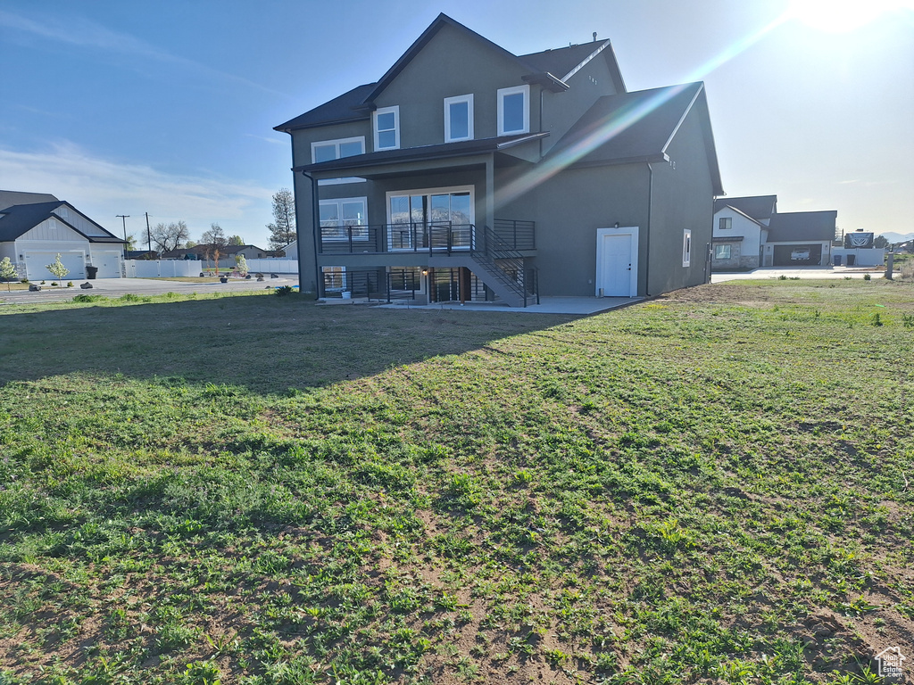 Rear view of property with stairs, stucco siding, a yard, and a patio