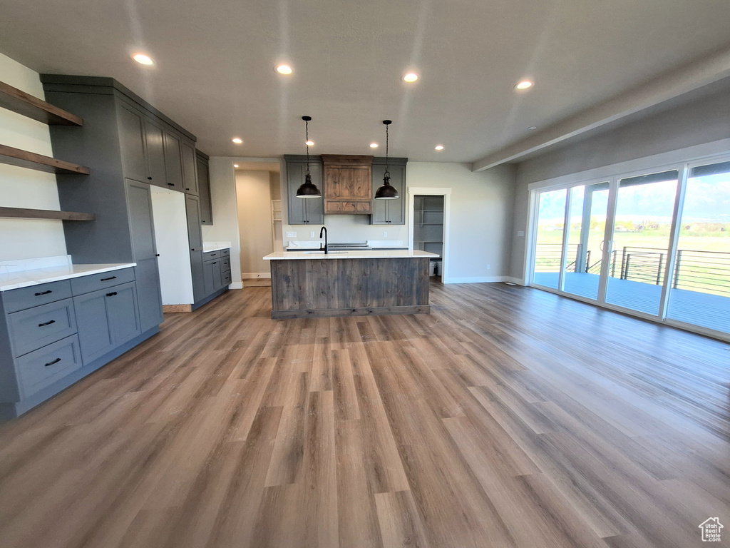 Kitchen featuring baseboards, open shelves, recessed lighting, wood finished floors, and a sink