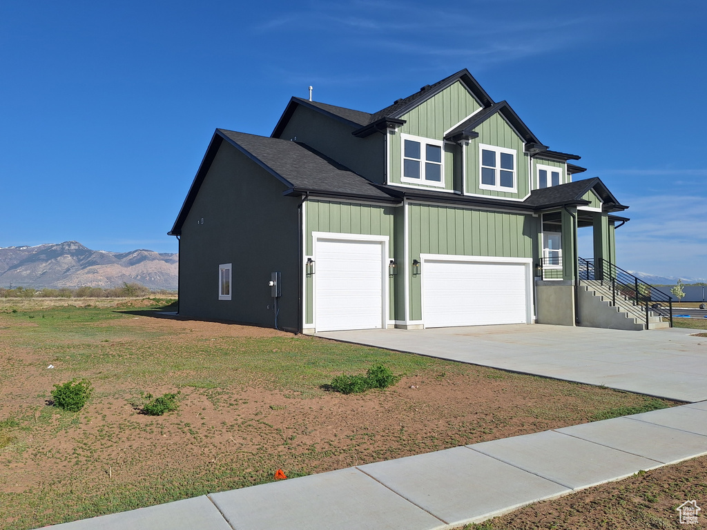 View of property exterior featuring concrete driveway, an attached garage, a mountain view, and a shingled roof
