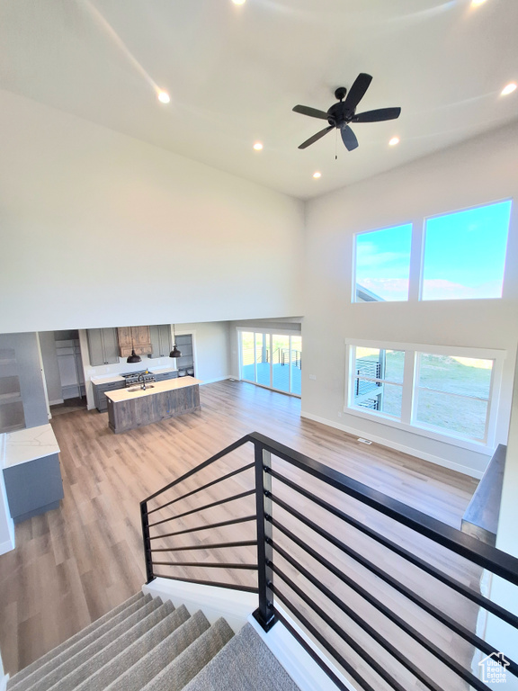 Stairs with wood finished floors, recessed lighting, and ceiling fan