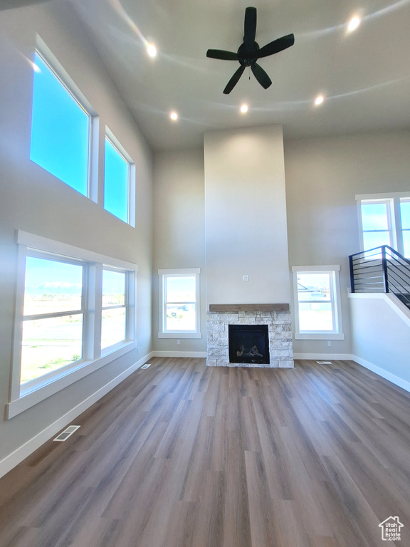 Unfurnished living room featuring baseboards, a high ceiling, wood finished floors, recessed lighting, and a ceiling fan