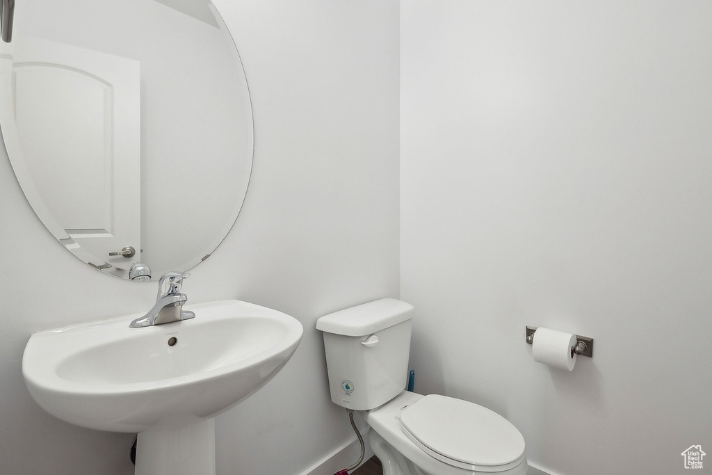 Bathroom featuring toilet, a sink, and baseboards