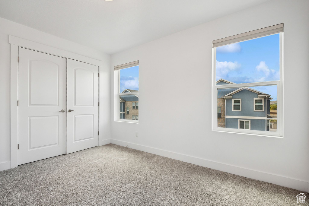 Unfurnished bedroom featuring baseboards, carpet, and a closet