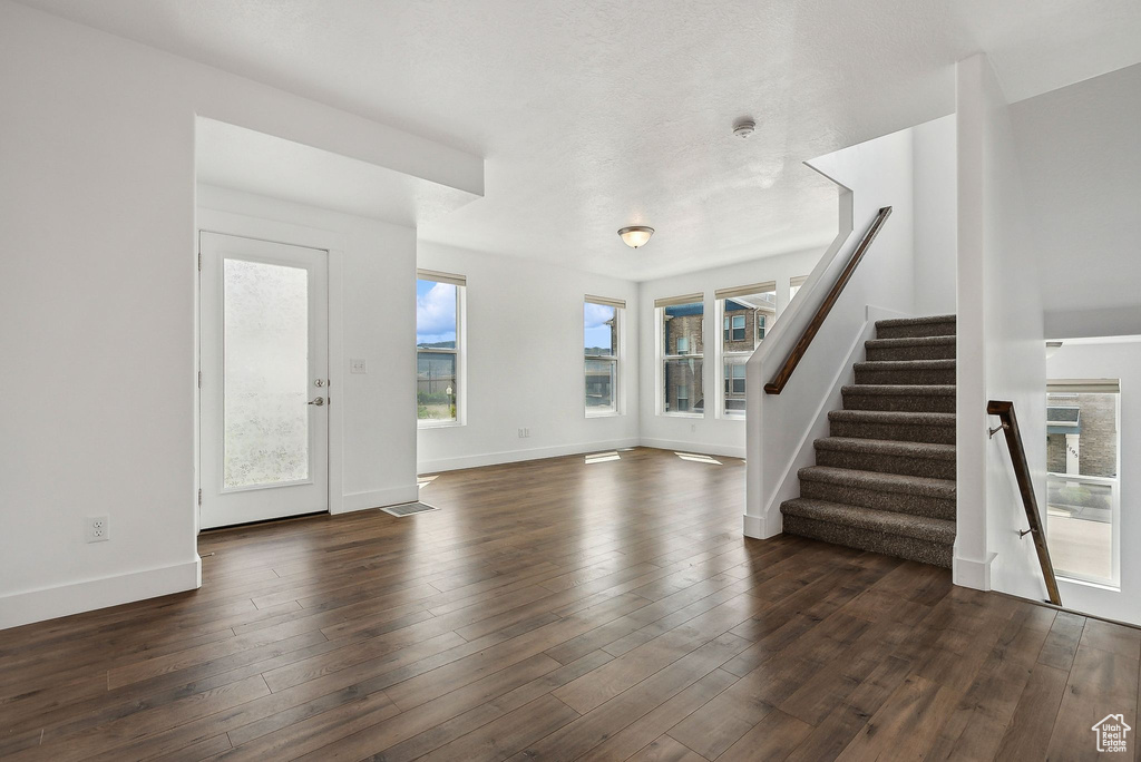 Entrance foyer with stairs, baseboards, and dark wood-type flooring