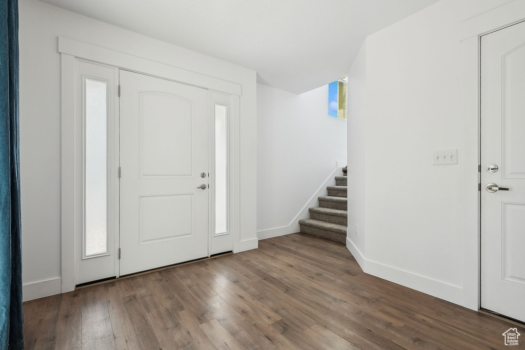 Foyer entrance with stairway, wood finished floors, and baseboards