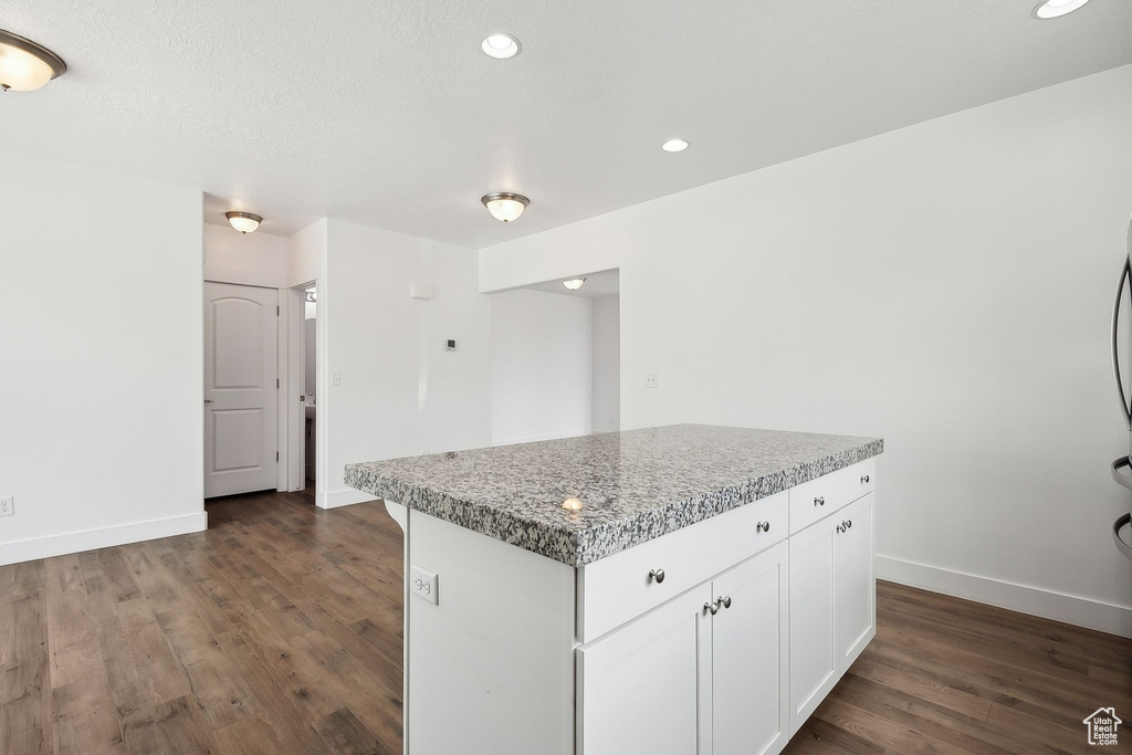 Kitchen with baseboards, dark wood-style flooring, white cabinetry, a kitchen island, and recessed lighting