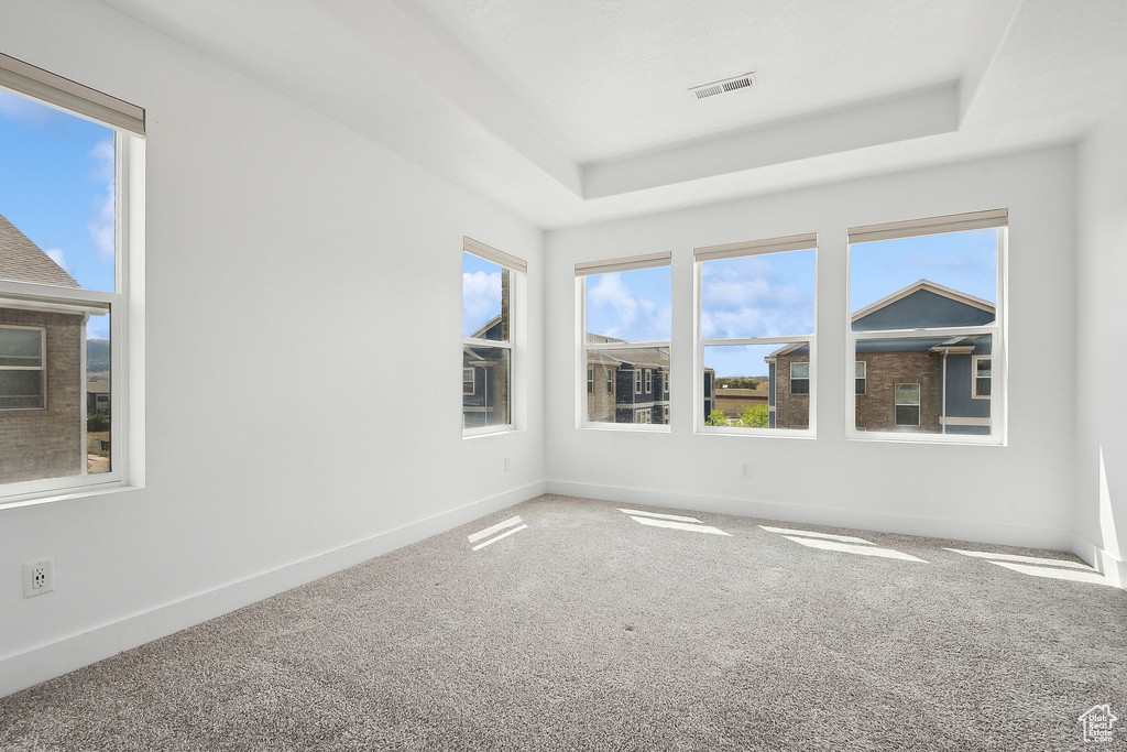 Empty room with a raised ceiling, carpet floors, and baseboards