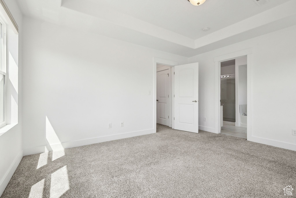 Unfurnished bedroom with light carpet, baseboards, and ensuite bath