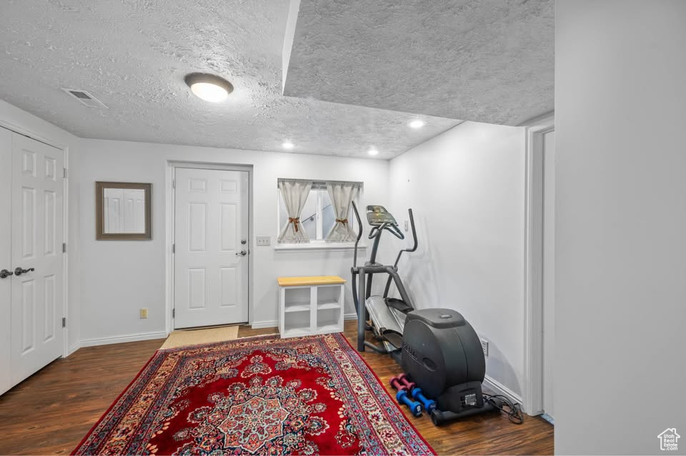 Workout area featuring wood finished floors, baseboards, recessed lighting, and a textured ceiling