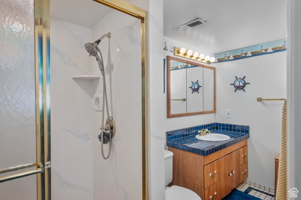 Bathroom featuring a stall shower, vanity, and toilet