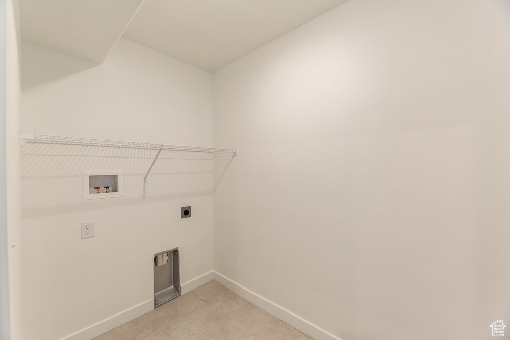 Washroom with hookup for an electric dryer, hookup for a washing machine, and baseboards