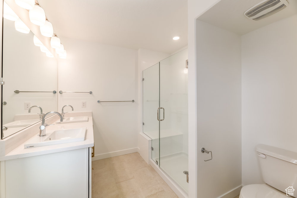 Full bath featuring a shower stall, toilet, recessed lighting, baseboards, and double vanity