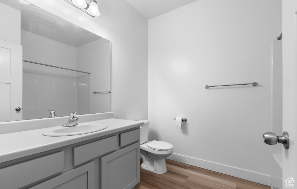 Bathroom with wood finished floors, baseboards, toilet, and vanity