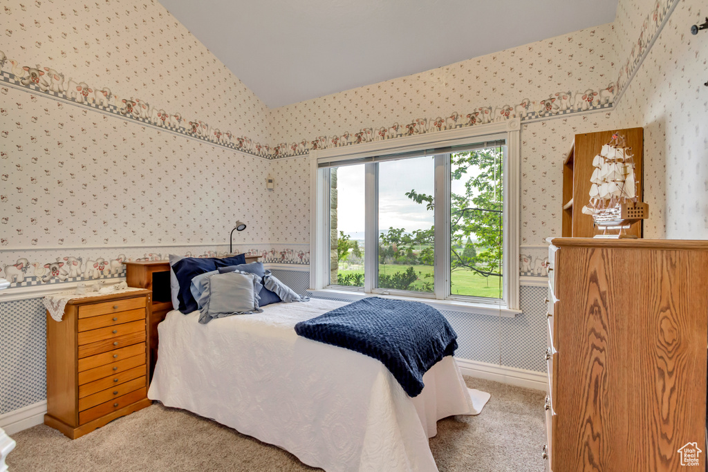 Bedroom featuring wallpapered walls, carpet, and lofted ceiling