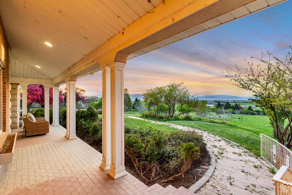 Patio terrace at dusk with covered porch and a yard