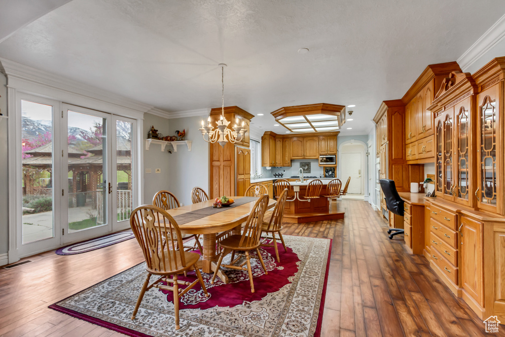 Dining area with hardwood / wood-style flooring, a chandelier, crown molding, and a desk