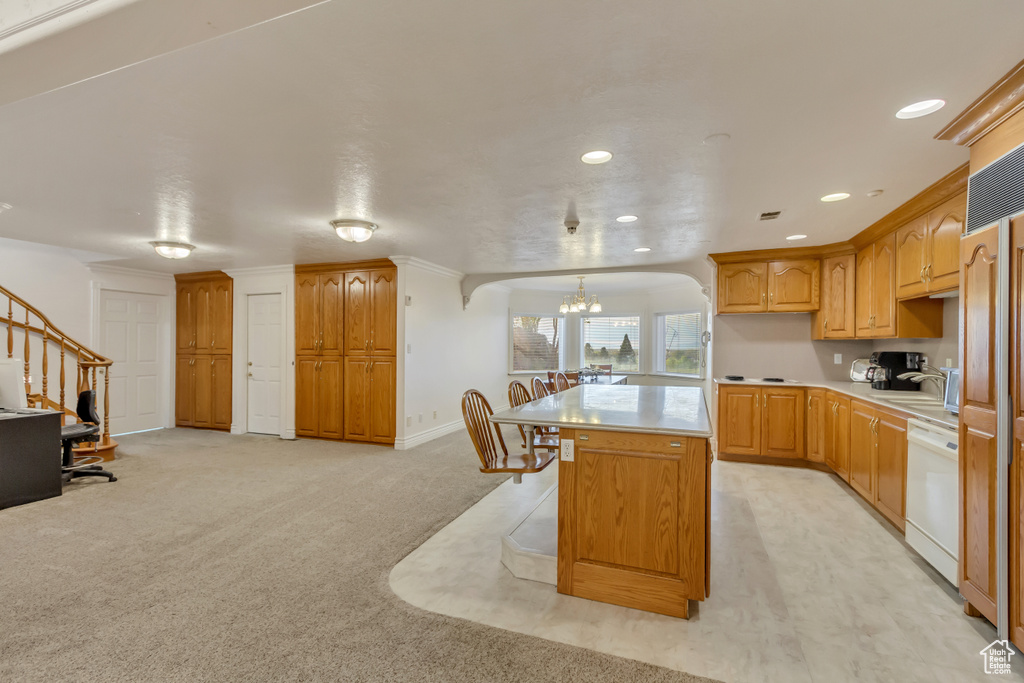 Kitchen featuring white dishwasher, a chandelier, light countertops, a center island, and recessed lighting