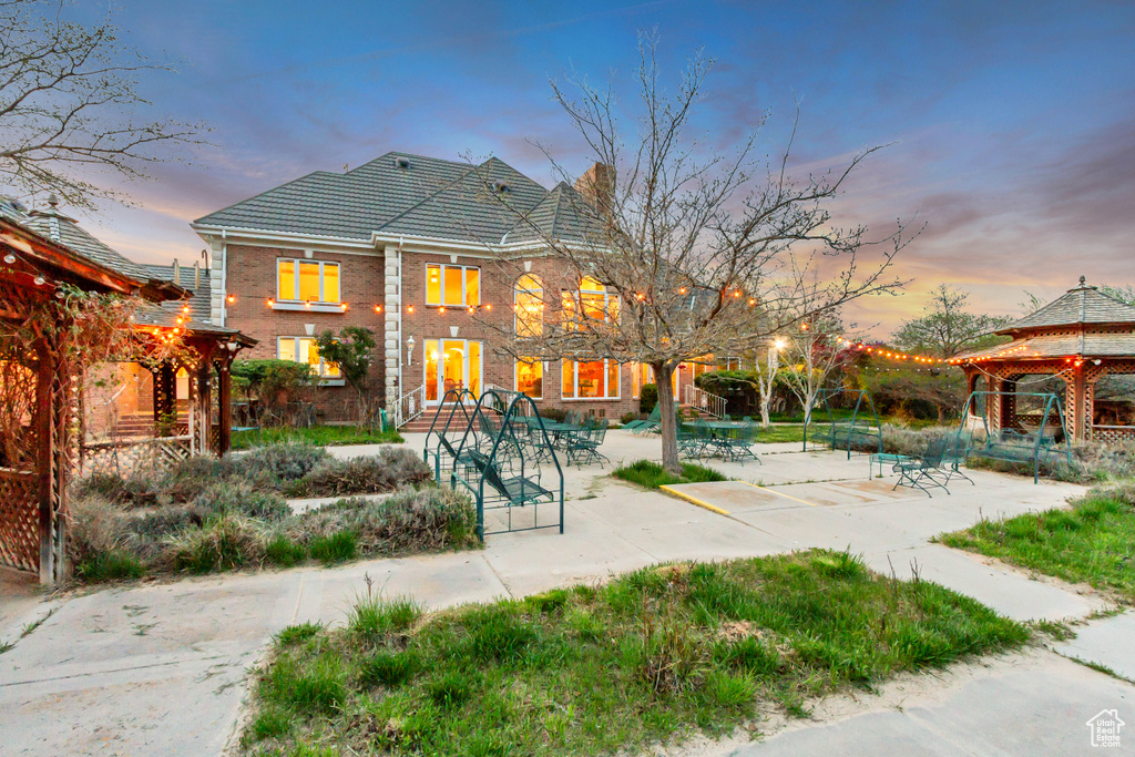 Back of property with a gazebo, brick siding, a tiled roof, and a patio