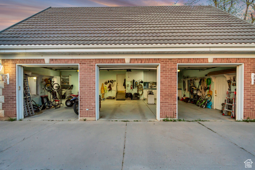 Garage at dusk featuring concrete driveway