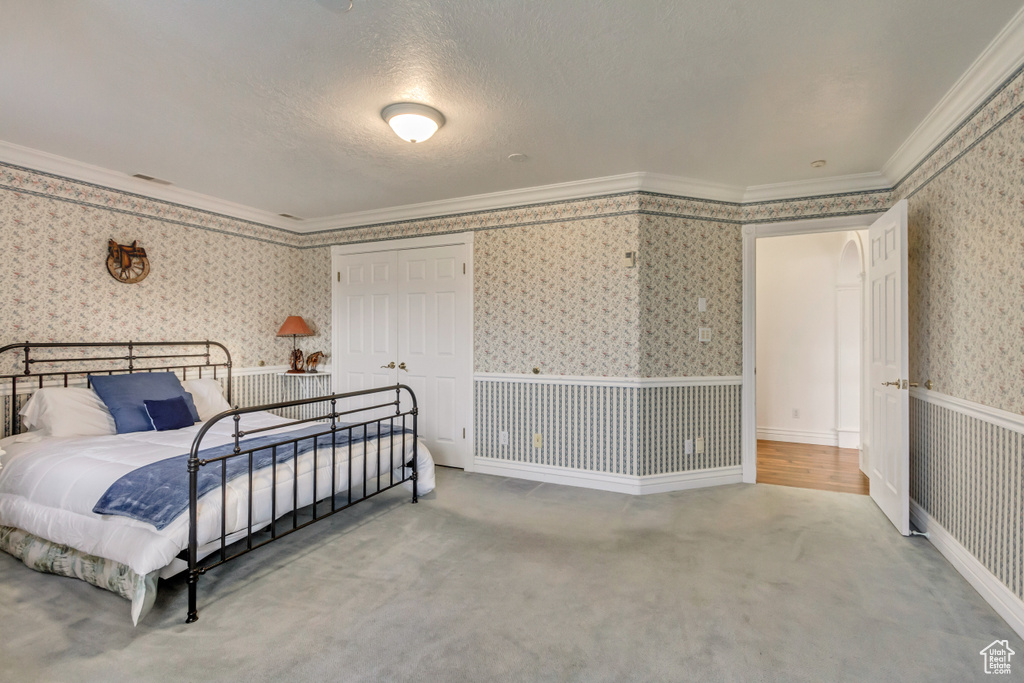 Carpeted bedroom with wallpapered walls and ornamental molding