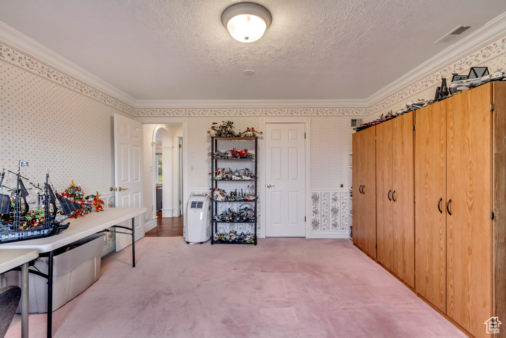 Carpeted home office with arched walkways, wallpapered walls, ornamental molding, and a textured ceiling
