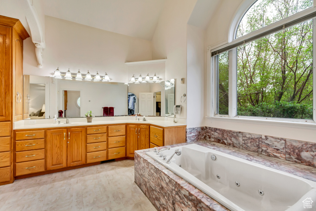Full bathroom with lofted ceiling, a whirlpool tub, and double vanity
