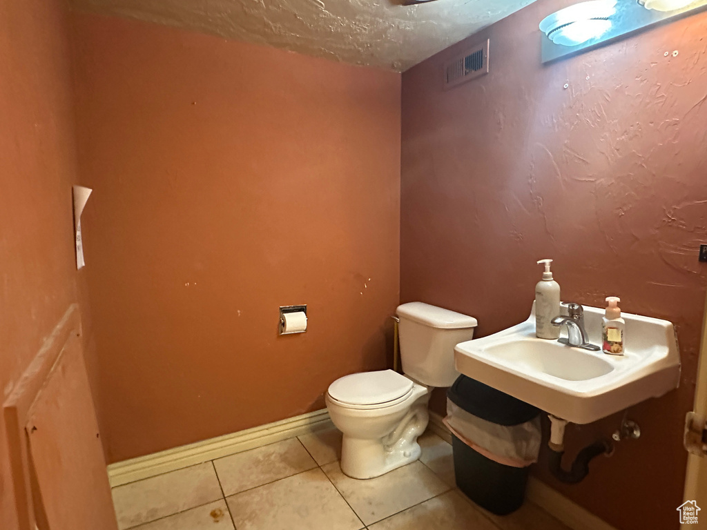 Bathroom with tile patterned floors, toilet, a sink, and a textured ceiling