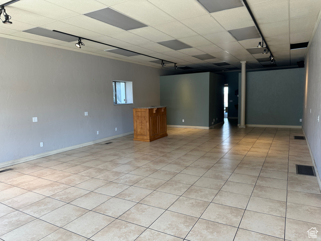 Spare room with track lighting, light tile patterned floors, baseboards, and a drop ceiling
