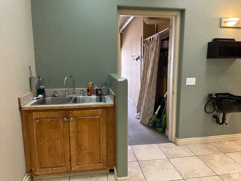 Bathroom featuring a sink, tile patterned flooring, and baseboards