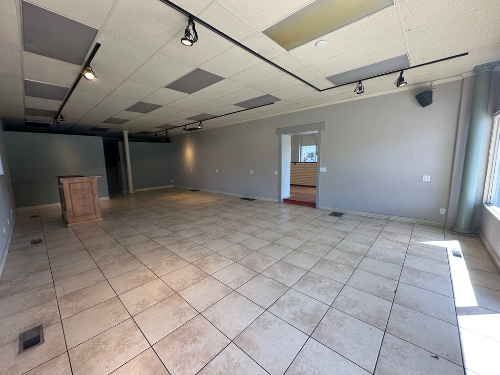 Unfurnished room featuring track lighting, light tile patterned flooring, a drop ceiling, baseboards, and healthy amount of natural light